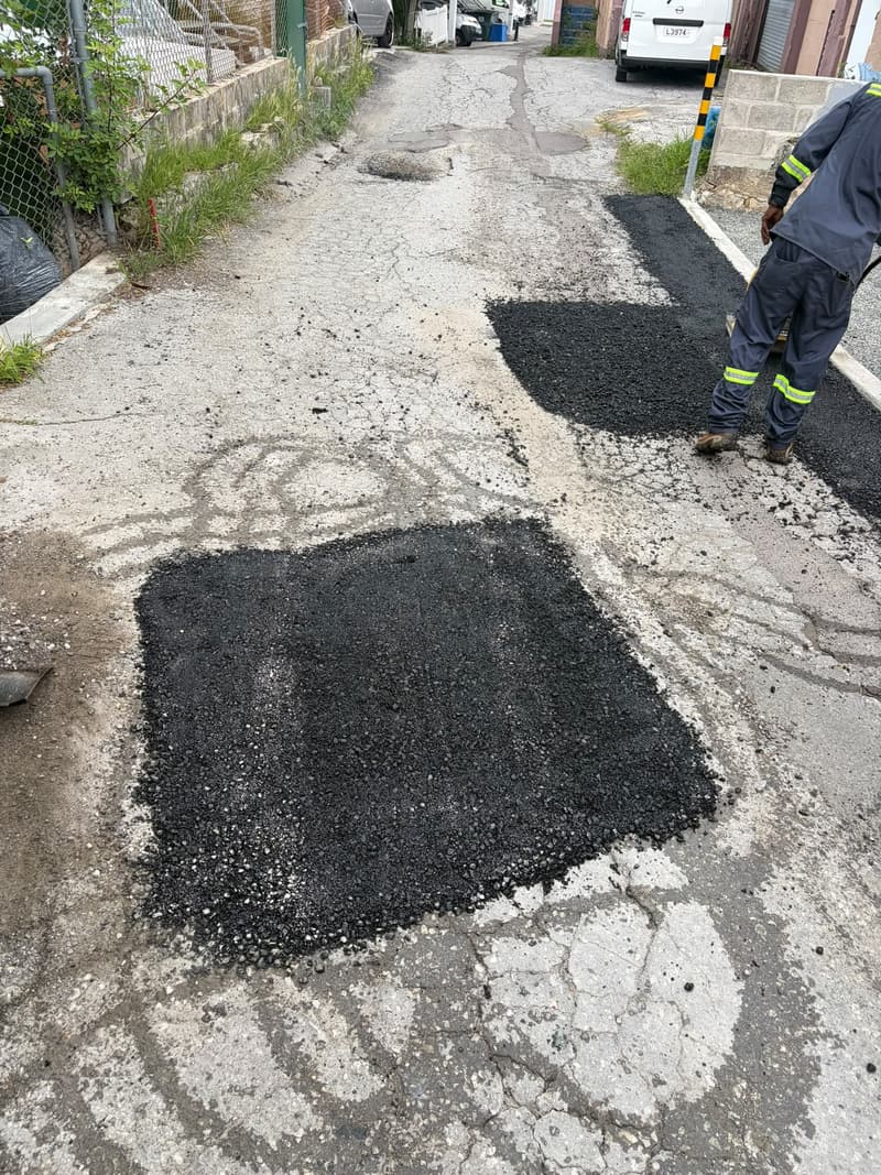 Quality Control Ltd crew member beside fresh asphalt patches in a narrow lane