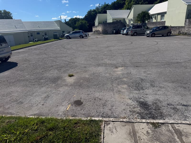 Worn, cracked asphalt parking lot at Bermuda Broadcasting Company before paving