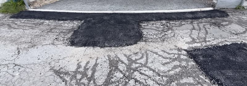 New asphalt patches along the curb and over the former potholes