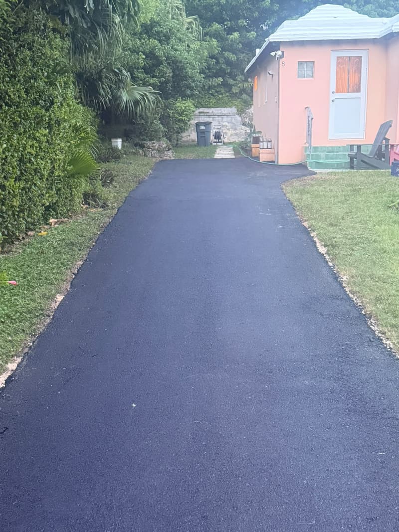 Newly paved black asphalt driveway beside a pink Bermuda cottage