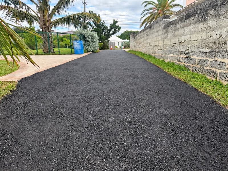 Freshly laid asphalt driveway beside a Bermuda limestone wall, paved by Quality Control Ltd