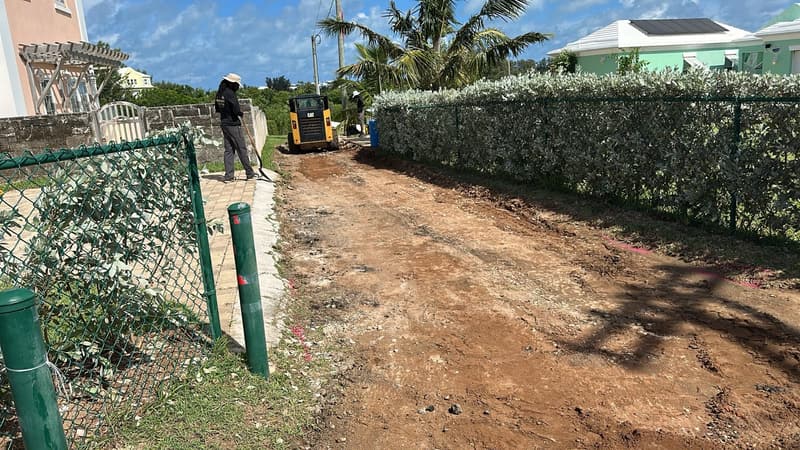 Old driveway removed down to the base, with a CAT skid steer and crew preparing the site