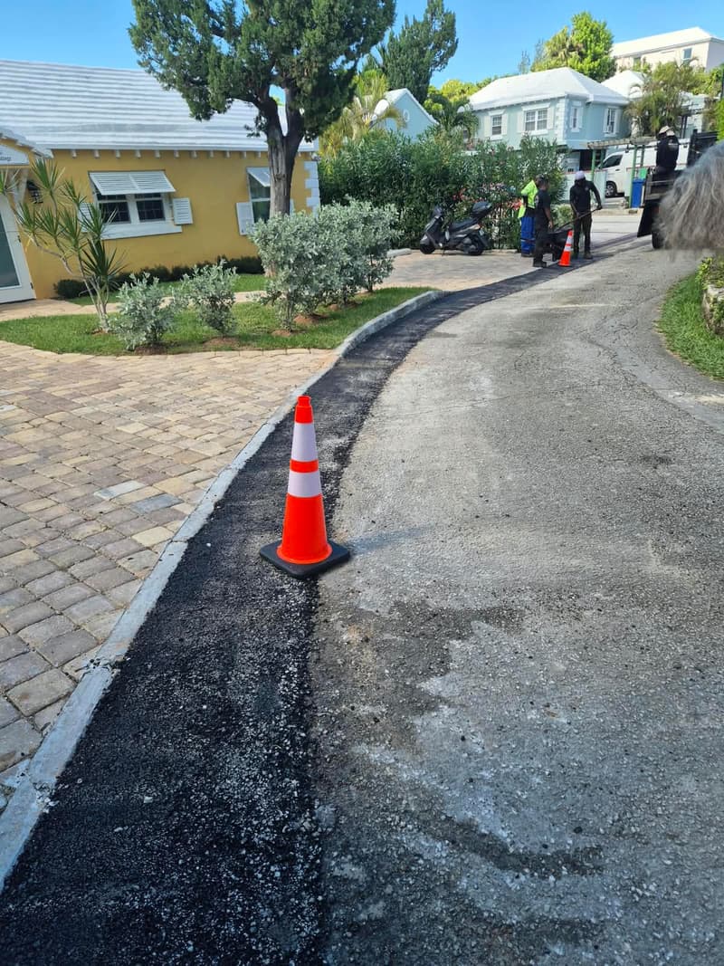 Quality Control crew finishing an asphalt ramp with a dump truck parked on the driveway