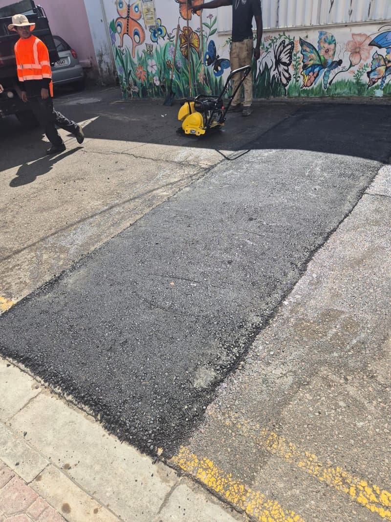 Quality Control Ltd crew compacting fresh asphalt with a plate compactor