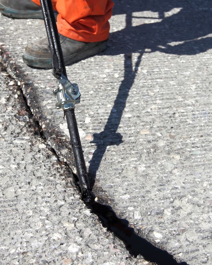 Crack in an asphalt surface being filled with sealant