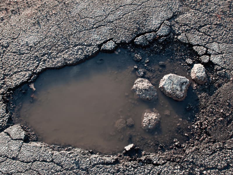 Pothole filled with water and broken stone